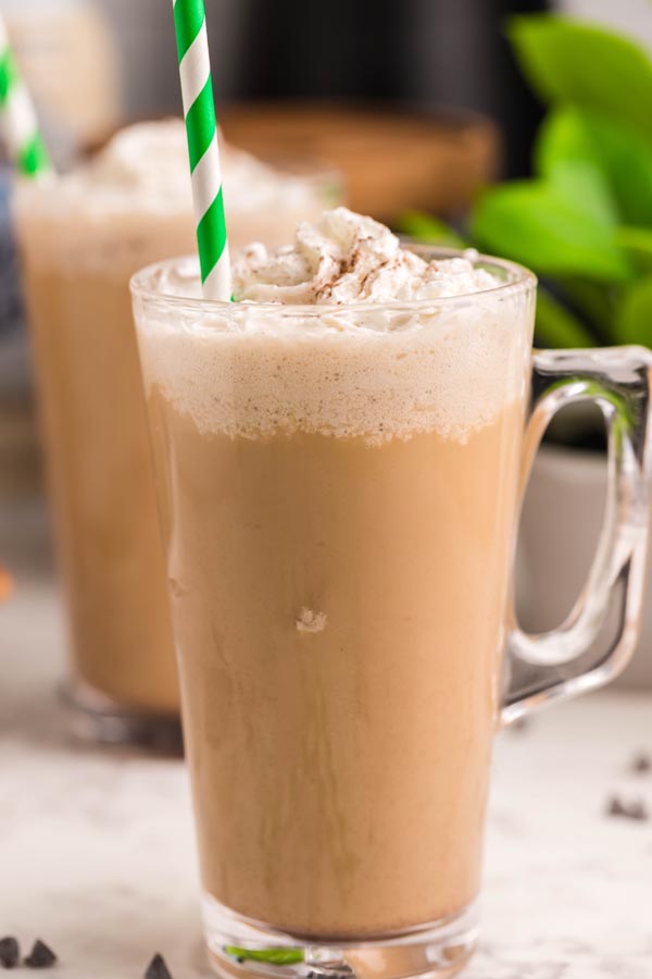 a frothy frozen coffee with a green and white striped straw