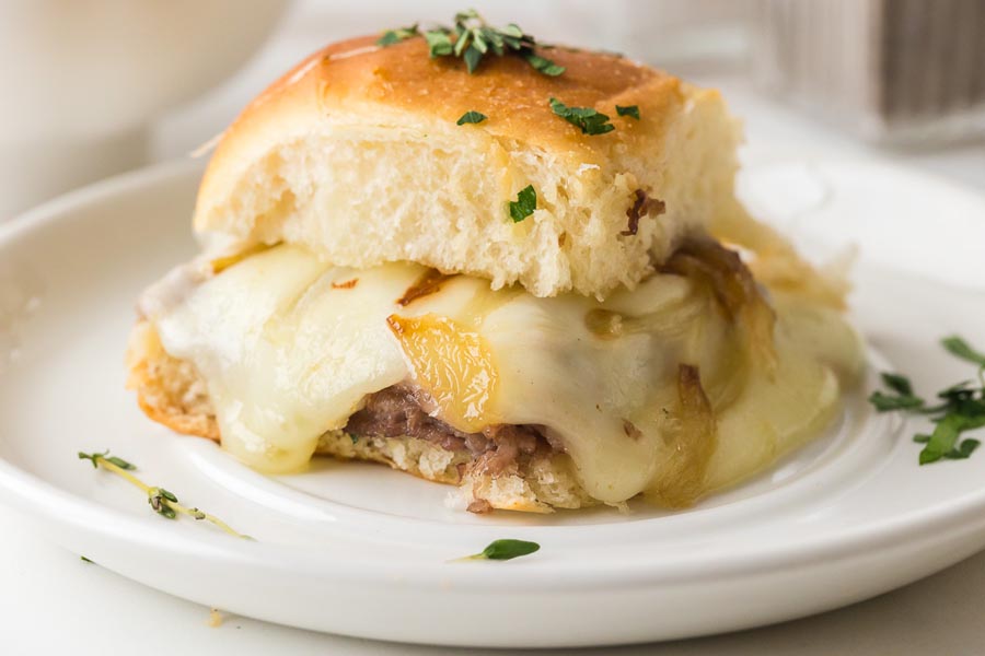 Close-up of a single keto French dip slider showing layers of roast beef, caramelized onions, and melted cheese.