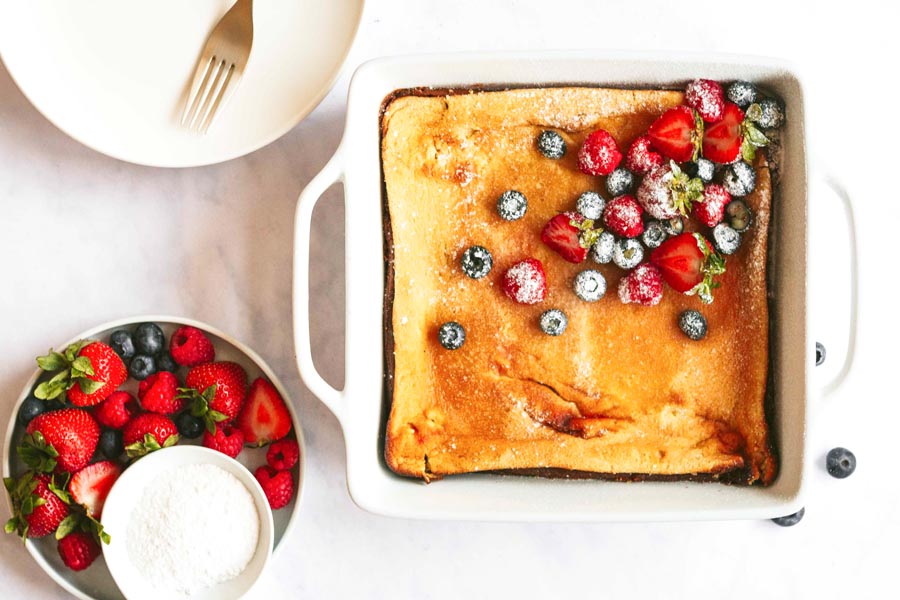 casserole bake in a white dish next to powdered Swerve and berries