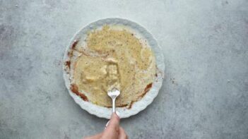 whisking a cinnamon egg mixture on a plate with a fork