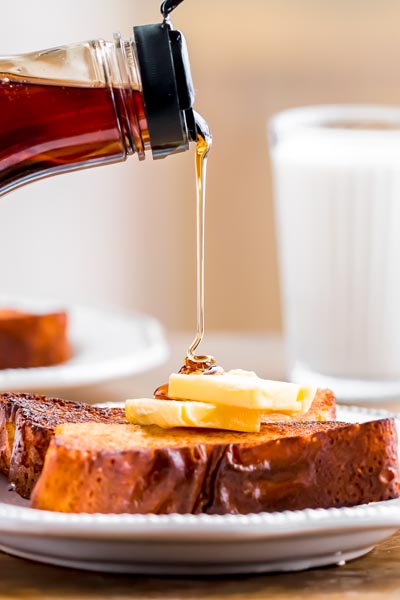 Pouring syrup on a slice of french toast topped with butter.