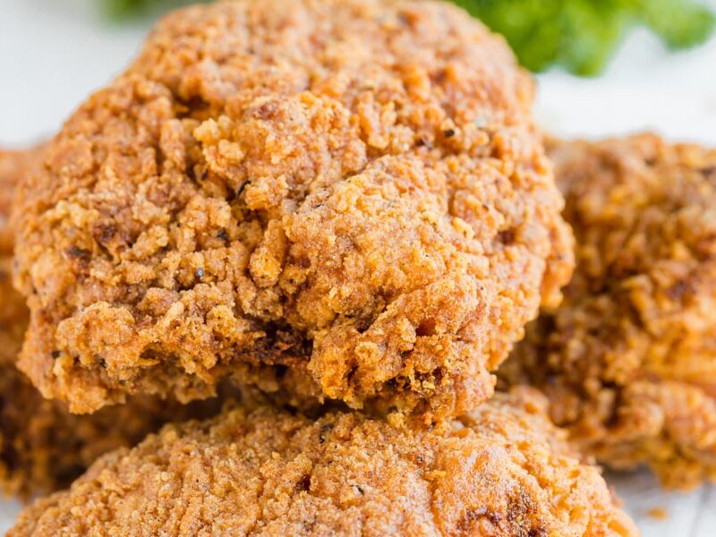 Close up of a fried chicken thigh with a crunchy crust.