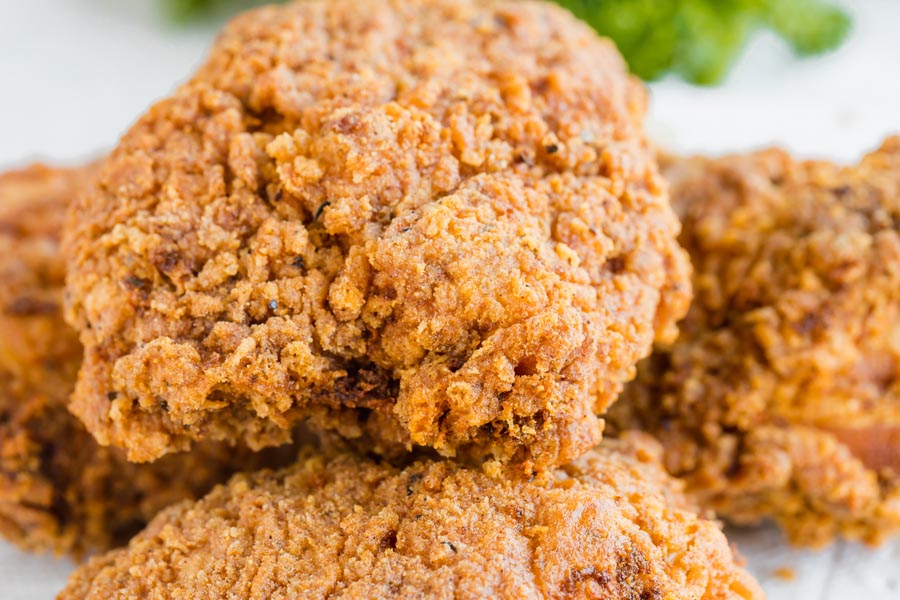 Close up of a fried chicken thigh with a crunchy crust.