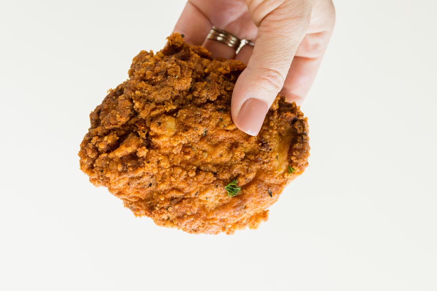 A hand holding a fried chicken thigh.