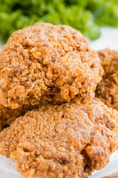 Crunchy fried chicken stacked on each other with greens in the background.