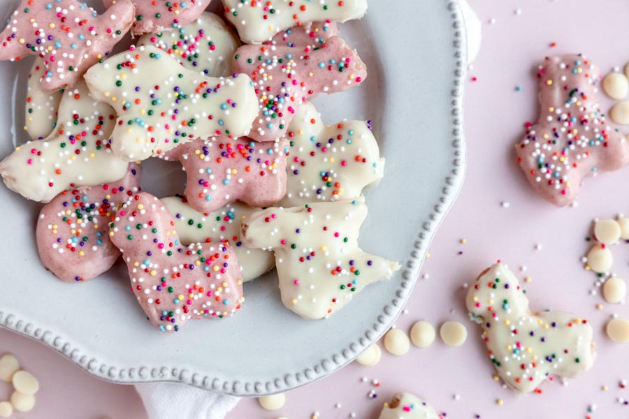 pink and white dipped keto frosted animal cookies on a plate with a white napkin