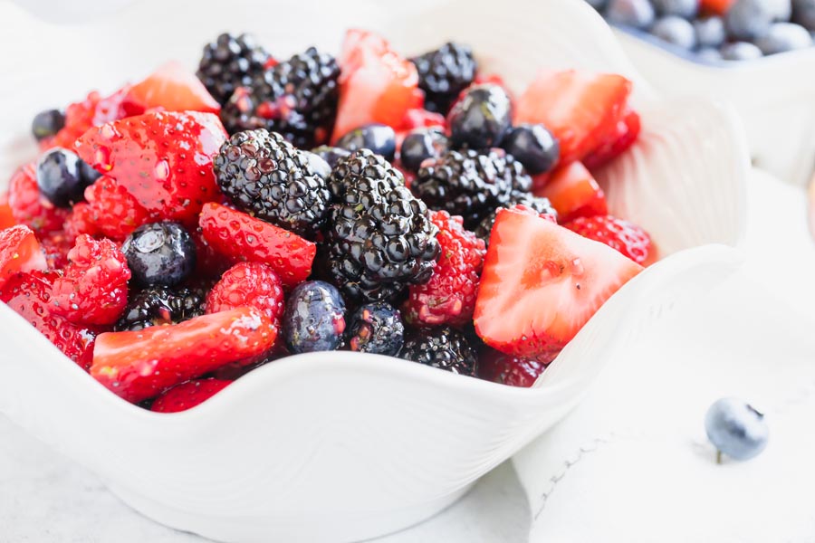 big juicy blackberries in a bowl with sliced strawberries