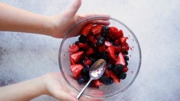 holding a bowl with mixed berries in it