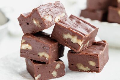 A stacked pile of rich keto fudge squares with chopped walnuts visible inside each piece.