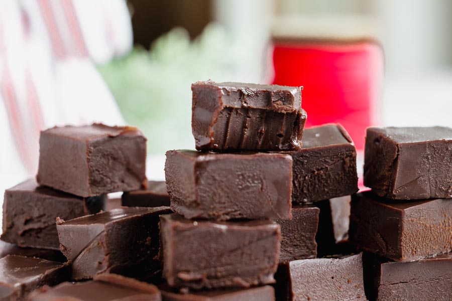 A stack of keto fudge squares with the top piece showing a clean bite revealing the creamy texture.
