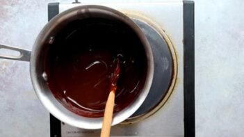 Melted chocolate being stirred in a saucepan until smooth and glossy.