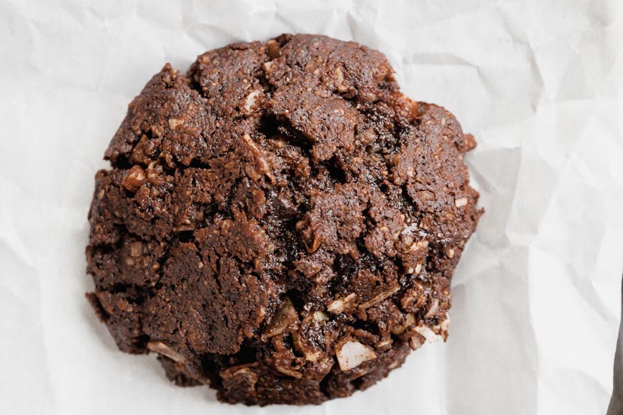 Close up of a fudgy chocolate cookie with coconut flakes inside.