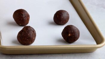 Cookie dough rolled into balls on placed on a parchment lined baking tray.
