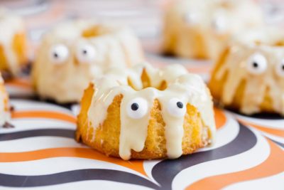 a small cake that looks like a ghost with white chocolate drizzled and candy eyes