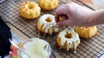 adding candy eyes to small bundt cakes drizzled with white chocolate