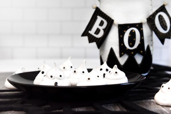 a bunch of white ghosts on a plate with a boo banner in the background