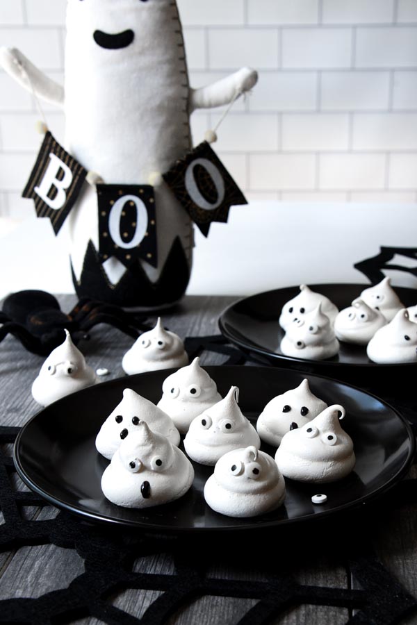 two black plates with ghost cookies on them