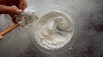 adding stiff meringue to a piping bag with a spatula