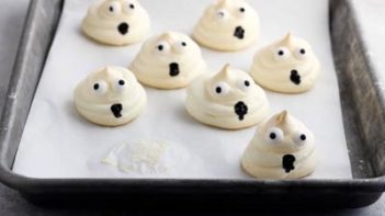 a baking tray with ghost cookies on it