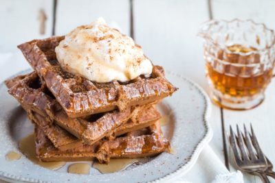 stack of keto gingerbread waffles with whipped cream and syrup