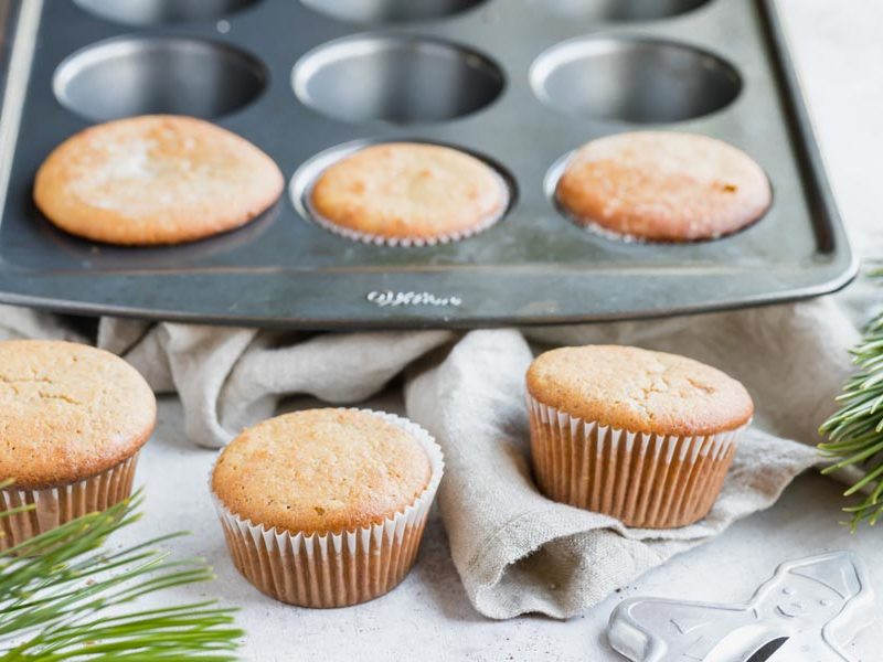 six muffins, three in a muffin pan and a gingerbread man cookie cutter peaking up