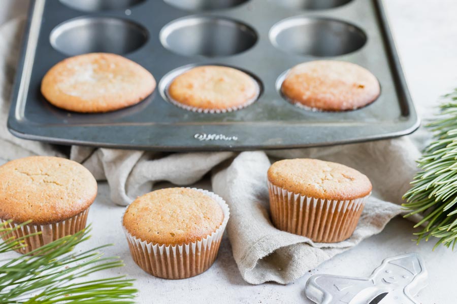 six muffins, three in a muffin pan and a gingerbread man cookie cutter peaking up