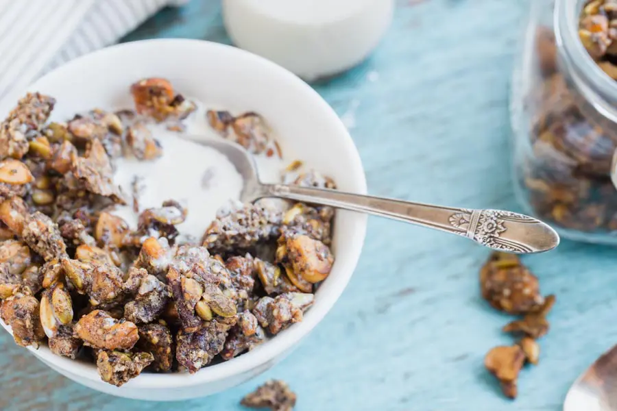 a spoon laying in a bowl of cream with granola