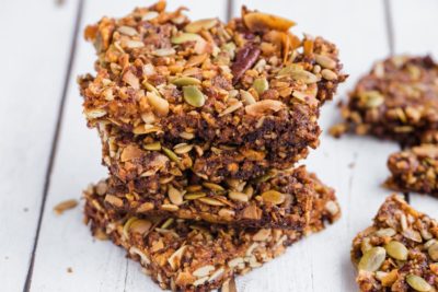 four granola bars stacked and filled with lots of seeds