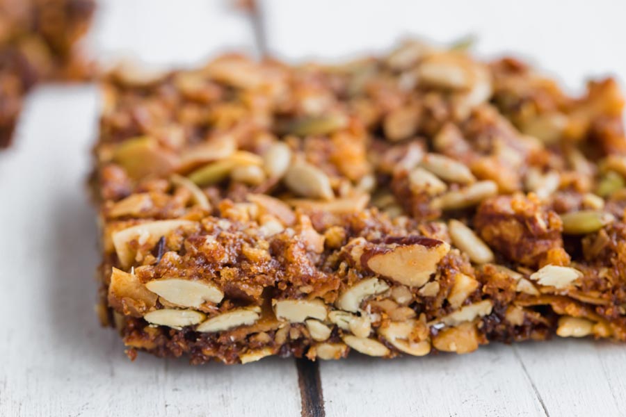 a sliced crispy granola bar showing layers of nuts and seeds