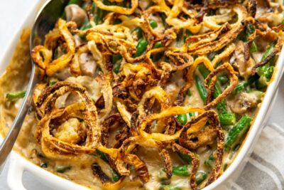 Homemade green bean casserole in a white baking dish topped with crispy fried onions and mushroom soup.