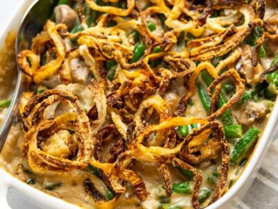 Keto green bean casserole with mushrooms and crispy fried onions in a white baking dish.