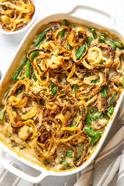 A casserole dish filled with green bean casserole with bright green beans and crispy onions.