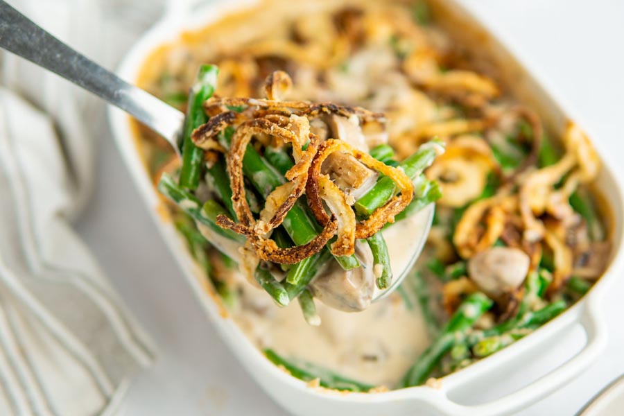 A serving spoon holding a serving of green bean casserole.