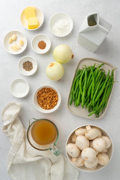 Ingredients for green bean casserole on display including mushrooms, green beans, onions, garlic and broth.