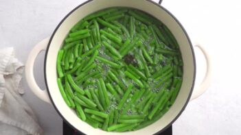 A pot of green beans simmering on a burner.