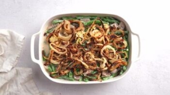 A casserole dish filled with green beans, creamy sauce and topped with fried onions.