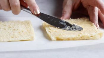 spreading butter on a slice of bread with a butter knife