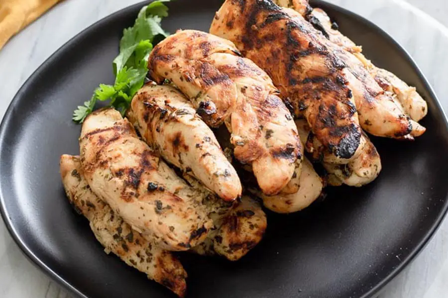 a pile of grilled chicken tender strips on a black plate