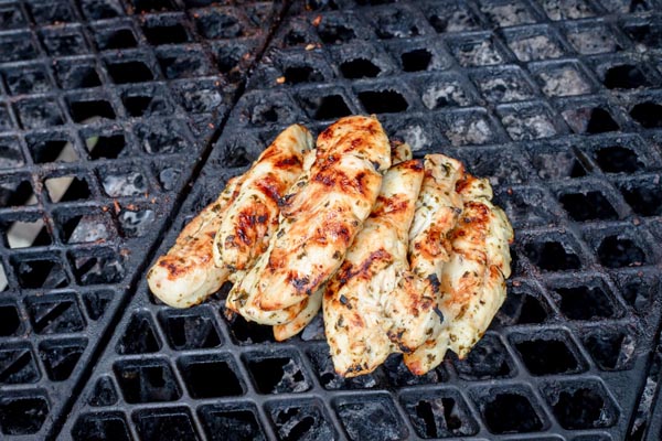 multiple chicken strips on a black grill grate