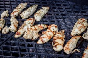lots of mini chicken tenders lined up on a grill