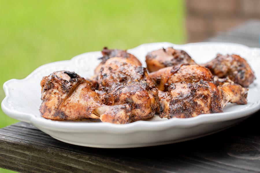 jerk chicken on a white plater on a patio table