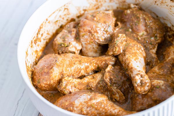 chicken legs marinading in jerk seasoning in a bowl