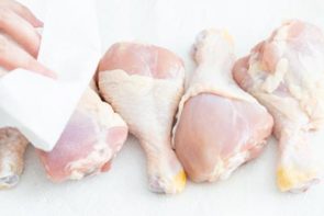chicken legs on a cutting board and patting them dry with a paper towl