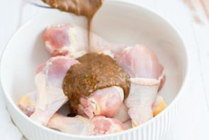 pouring jerk marinade onto chicken legs in a bowl