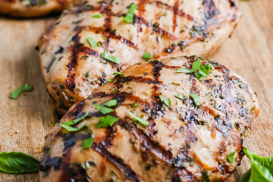 close up of grilled chicken topped with chopped herbs