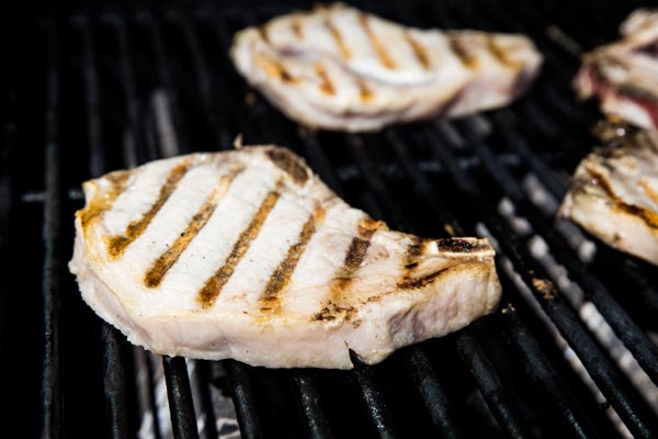 bone in pork chops on a grill with grill marks on top of the chops