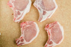 four bone-in pork chops with salt sprinkled on top
