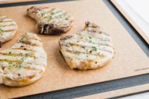 melted butter mixture on top of a grilled pork chop on the cutting board