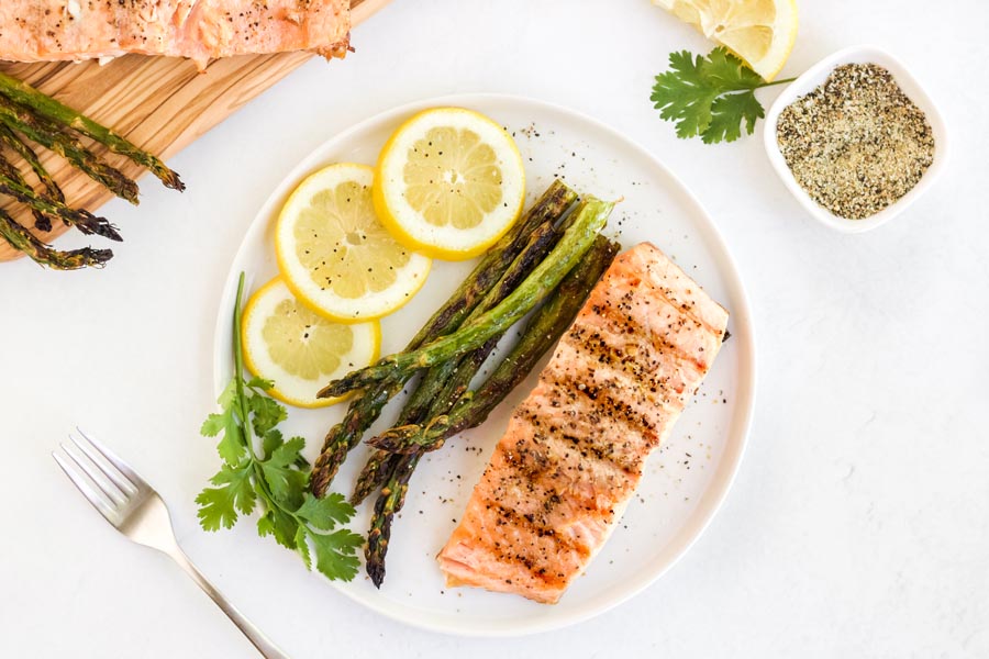 overhead view of grilled salmon and asparagus with lemon slices on a plate