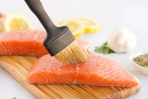 brushing pink salmon fillet with olive oil and a basting brush